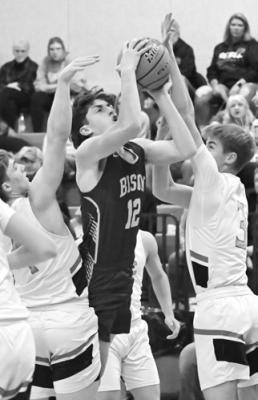LUKE MCHARGE attempts to score in the paint through a pair of Arcadia/Loup City defenders on Friday night. Photo by Michael Happ
