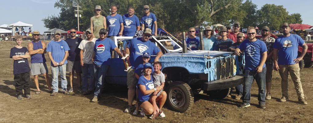 PARTICIPANTS in this year’s Watermelon Days Demolition Derby in St. Libory gathered together to recognize Sutton Hake of Palmer as the derby’s top fan. Above, Hake is pictured with the drivers during this year’s derby, who wore their blue—the color of Leukodystrophy awareness—Sutton Squad t-shirts in support of the Palmer youth. Courtesy Photo