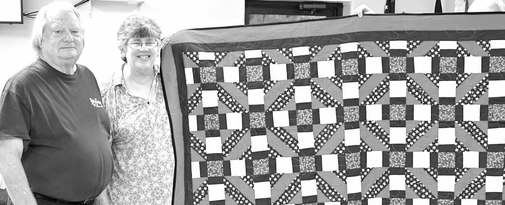 Wrapped in Community Love Jim Larson, For last Tuesday will be a day he remembers for a long time thanks to the generosity of Linda Jensen. Both smile while Linda holds onto a quilt that she made to honor Larson with during a Quilt of Valor presentation at the American Legion Post #6 meeting. Jensen also has been busy creating another special quilt that will be used in a raffle to raise funds for the Post and will be raffled on Veteran’s Day.