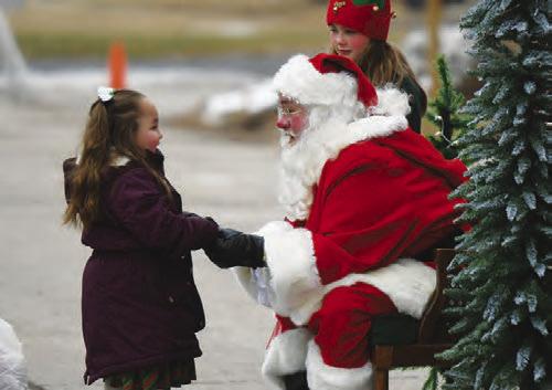 SANTA CLAUS shares a joyful moment with a young Christmas Celebration-goer outside Central City Elementary School.