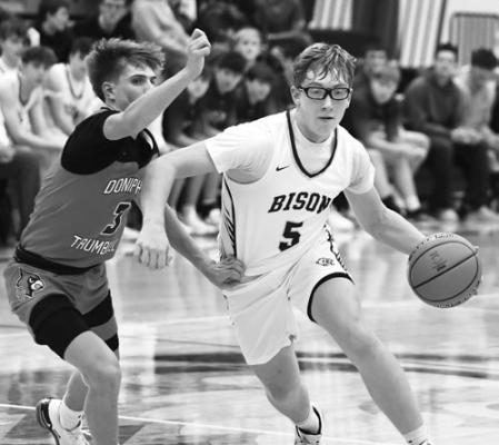 LOGAN VAKINER drives to the basket around Doniphan-Trumbull’s Kaser Johnson in Friday’s battle between the Bison and Cardinals. Photos by Jordan Coslor