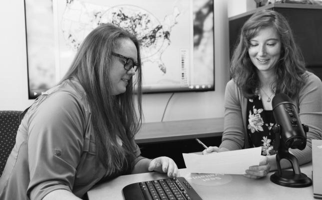 LINDSAY JOHNSON AND EMILY CASE-BUSKIRK collaborate on the script for an upcoming episode of the “Drought Download” while a previous episode plays in the background. Russell Shaffer | IANR Communications