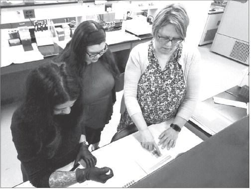 RESEARCH TECHNICIAN Petra Rose (left) pipettes buffers, antibody and protein samples into a western blot plate to be processed while Dr. Jennifer Wood (right) explains the protocol steps to Rebekah Lanning (center), a graduate rotation student in the Complex Biosystems program. Photo by Eric Buck