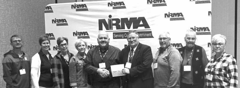 A group of Merrick County officials receive a dividend check presented by NIRMA board of directors member Darrell Zabrocki, who is a Seward County Commissioner. Pictured from left are: Brent Kunze, Jen Meyers, Carolyn Kucera, Trish Strobel, Roger Wiegert, Darrell Zabrocki, Edward Dexter, Jan Placke, and Theresa Good.