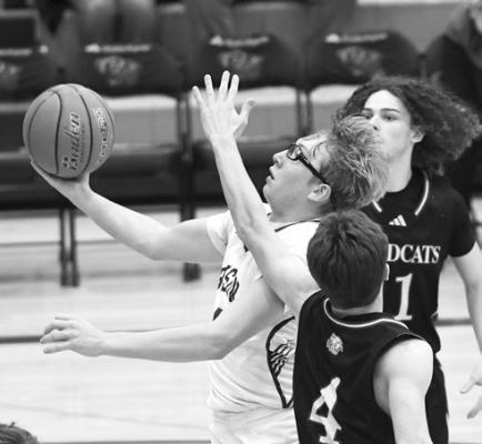 LOGAN VAKINER drives to the basket and lays it in through two St. Paul defenders in last Tuesday’s 69-45 loss to the Wildcats. Vakiner finished the contest with four points and four assists. Photos by Jordan Coslor