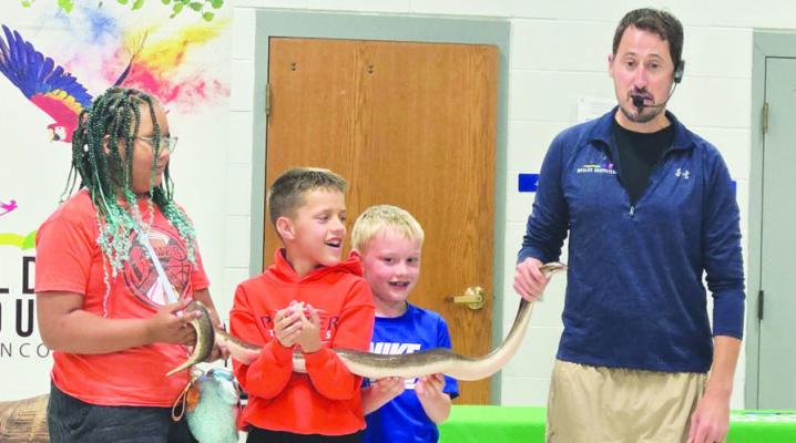 from Gretna brought six animals to visit participants in Palmer’s summer reading program last week. The animals were part of a fun, educational, and interactive forty-five minute presentation. Above, Kip Smith helps participants handle one of the animals during the event.