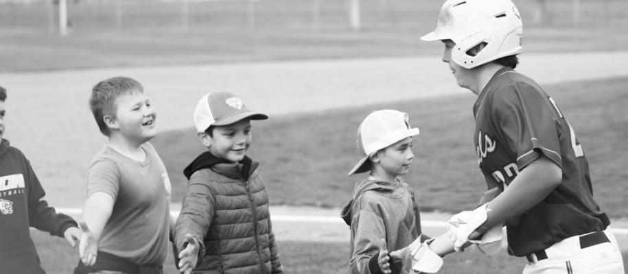 CENTRAL CITY/CENTURA’S CONNER ERIKSON gives high fives to some of the community’s baseball enthusiasts last Thursday night prior to the start of the Kernels’ game against Twin River. Pre-game festivities last week featured a variety of events involving youth players, with the Kernels topping off the night with an 11-1 victory. Photo by Jordan Coslor