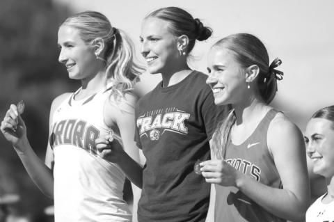 AVA CALL shows off her gold medal from the top of the medal stand after winning the 400-meter dash.