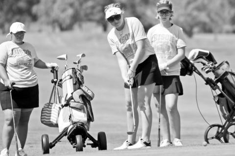 KELLSIE KUNZE attempts to sink a putt while teammates Kaydence Dettman and Karstyn Colclasure watch. The team of Colclasure, Dettman, and Kunze carded a ninety-five in Central City’s home scramble last Thursday. Photos by Jordan Coslor
