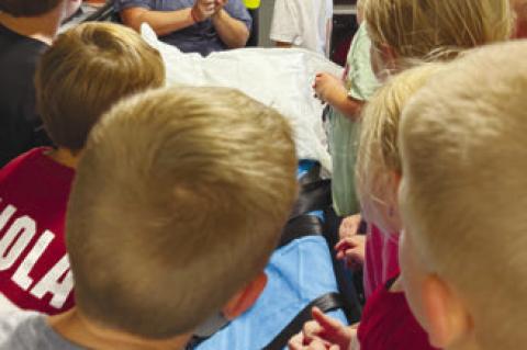 KINDERGARTENERS at Palmer Elementary School crane their necks to get a good look at the Palmer Rescue Squad’s ambulance during the class’s visit to the Palmer Fire Station last week as a part of National Fire Prevention and Safety Week. Helping guide the tour of the ambulance is Amber Smith Courtesy Photo